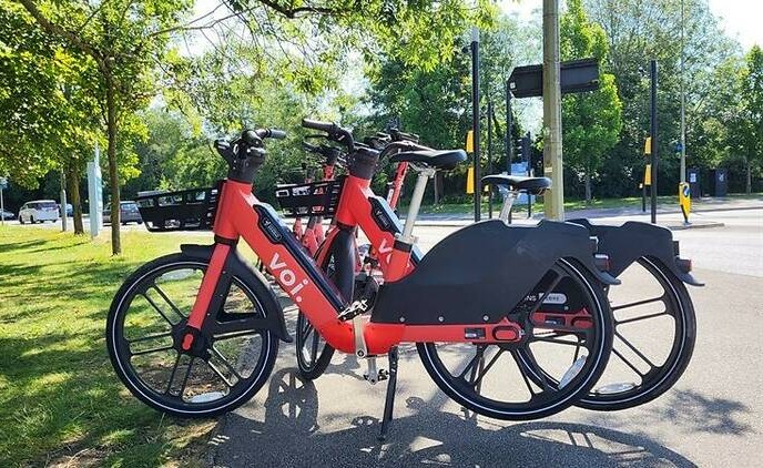 Voi e-bikes parked on the side of a footpath